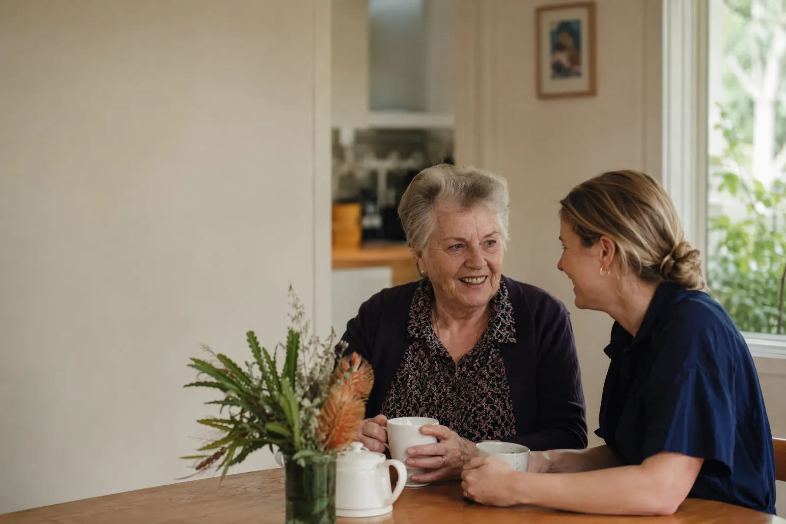 A care worker sharing a warm conversation with an older woman in her own home